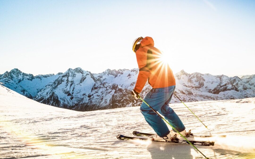 Adulte qui skie en haut d'une piste avec les montagnes en arrière-plan