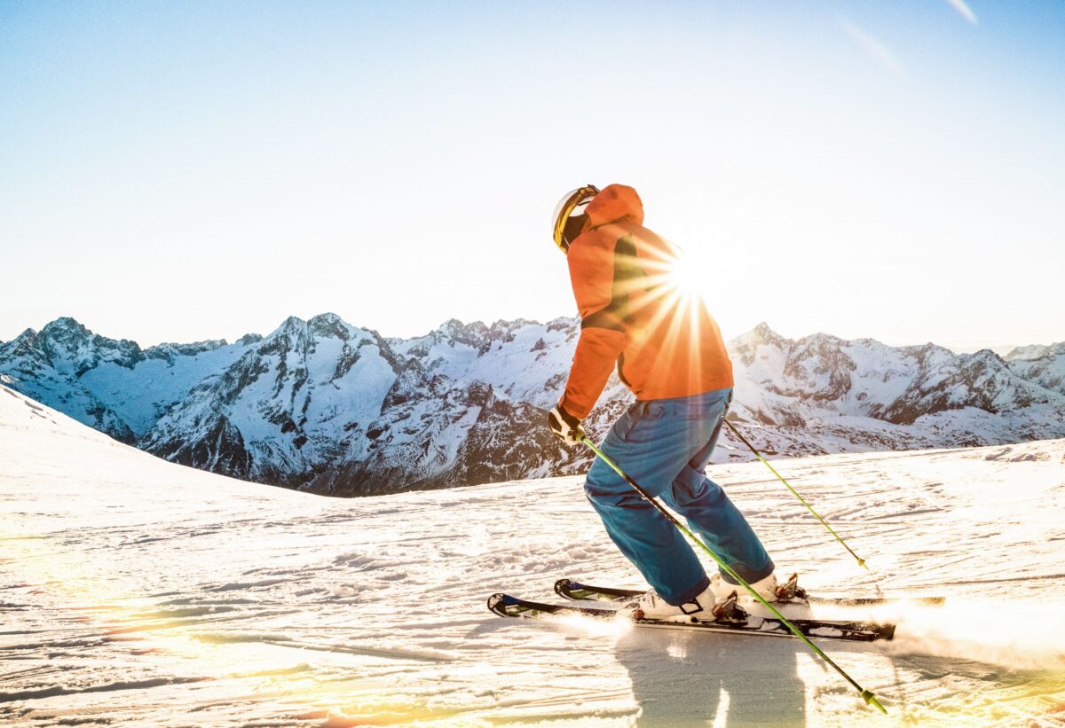 Adulte qui skie en haut d'une piste avec les montagnes en arrière-plan